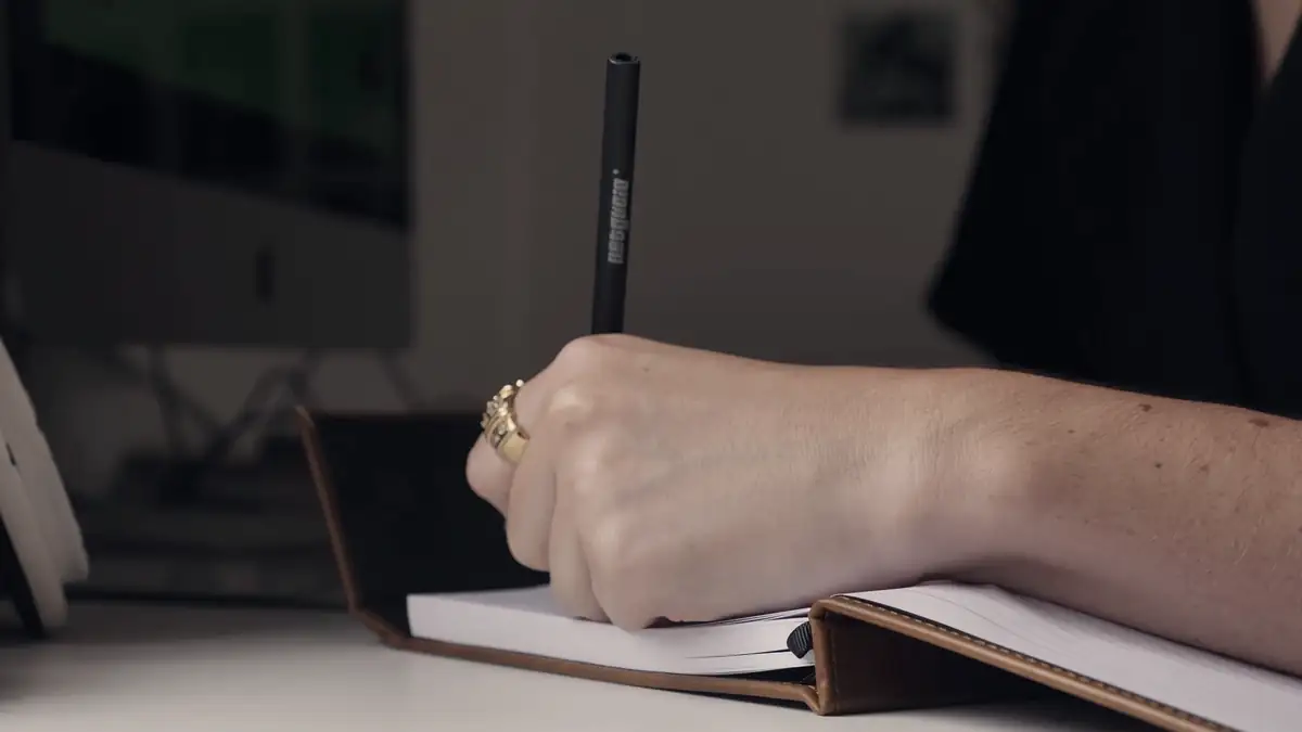 A hand writing in a notebook