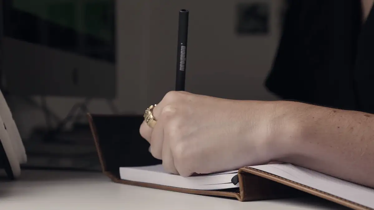 A hand writing in a notebook