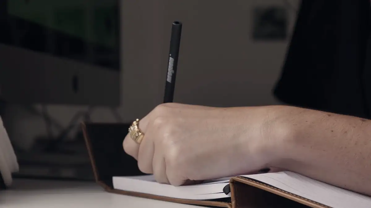 A hand writing in a notebook
