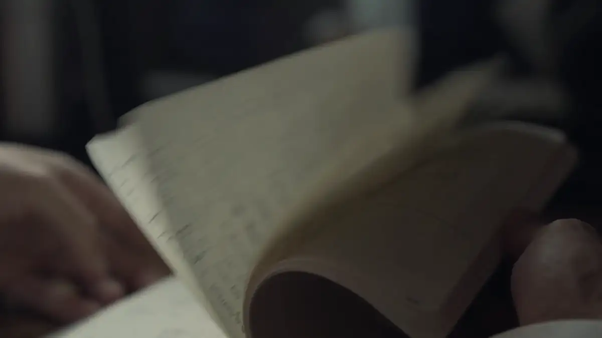 Hands turning the pages of a notebook in low light