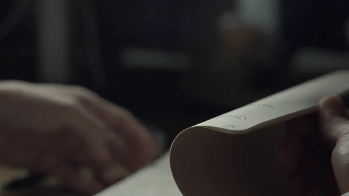 Hands turning the pages of a notebook in low light