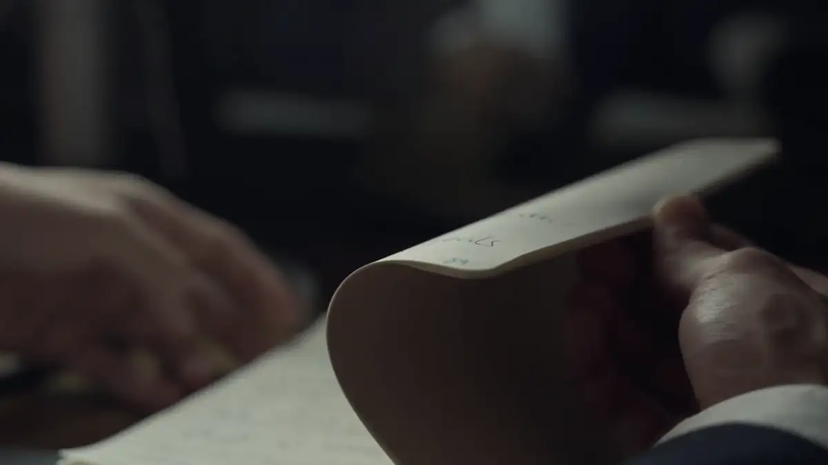 Hands turning the pages of a notebook in low light
