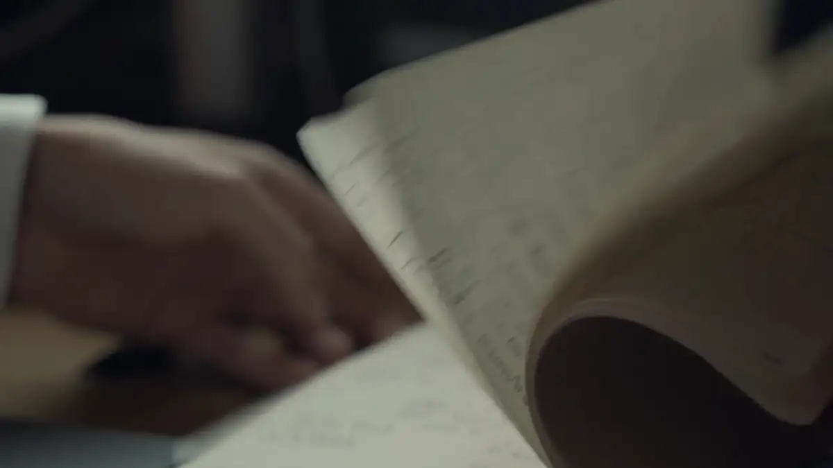 Hands turning the pages of a notebook in low light